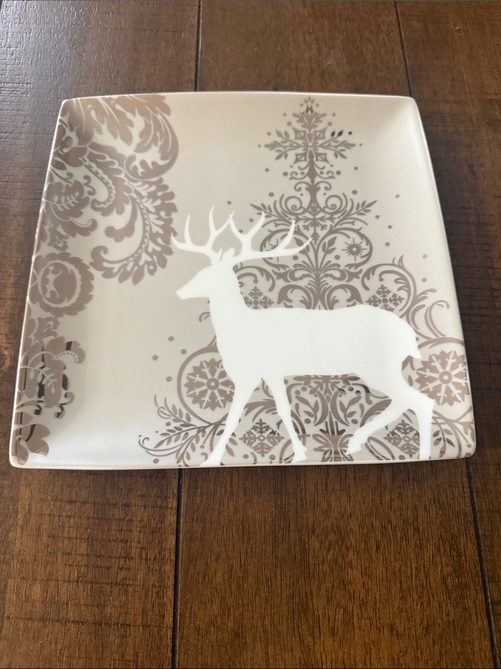 Noble Excellence square salad plate features a white reindeer silhouette surroun